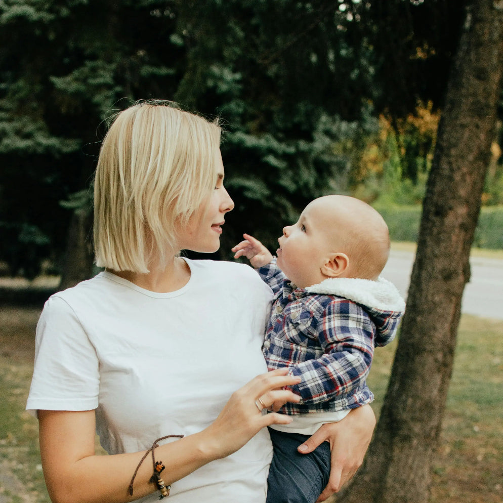 Jeune maman portant son bébé lors d’une balade en plein air.